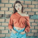 Fashionable woman in casual clothes posing against a brick wall.