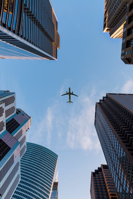 Airplane flies over Chicago's modern skyscrapers against a clear sky, highlighting urban architecture.